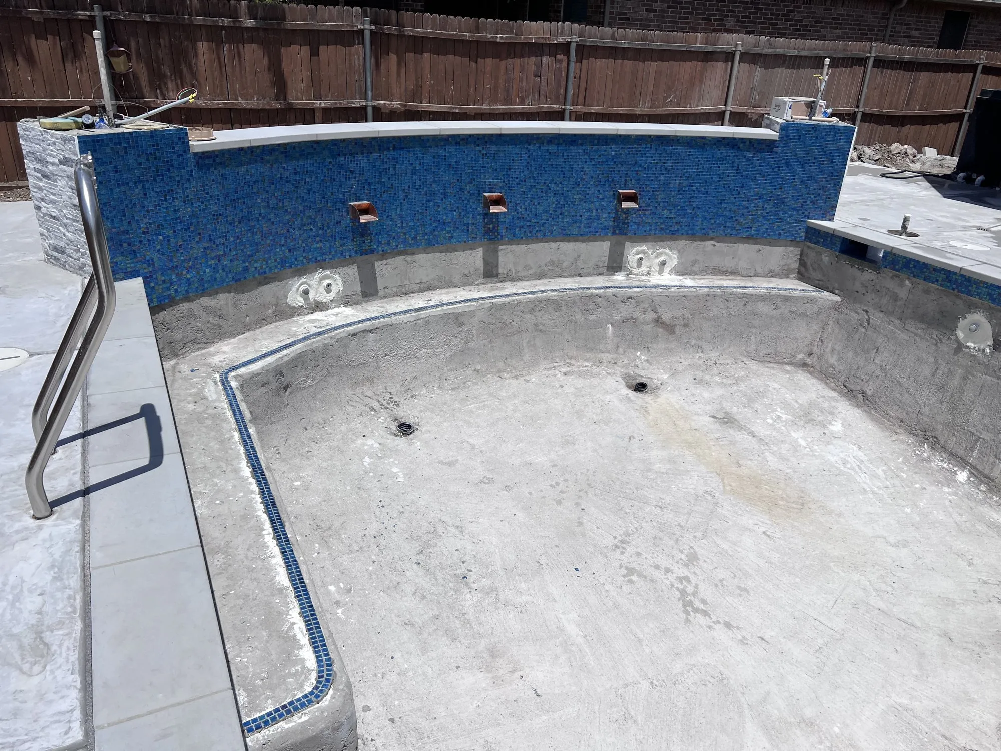 Blue waterline tile, three scuppers, and light coping on a Lucent pool build