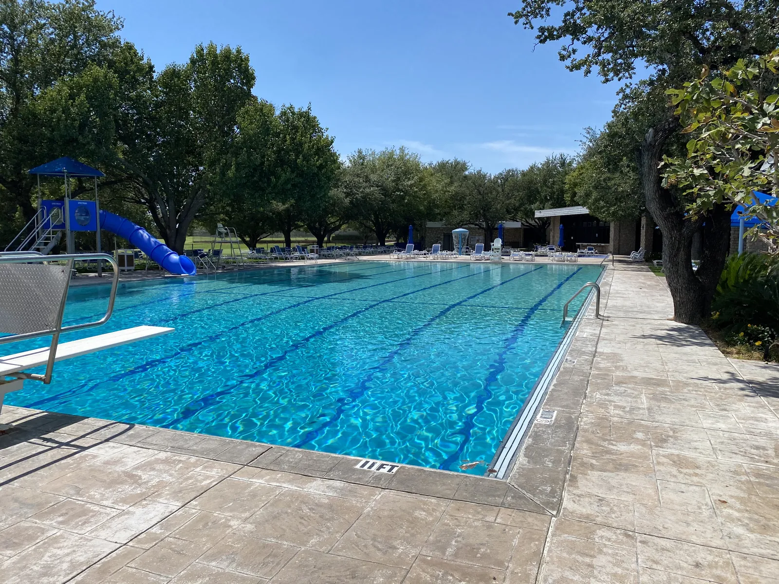 Country club lap pool with lane lines, a diving board, and a blue slide