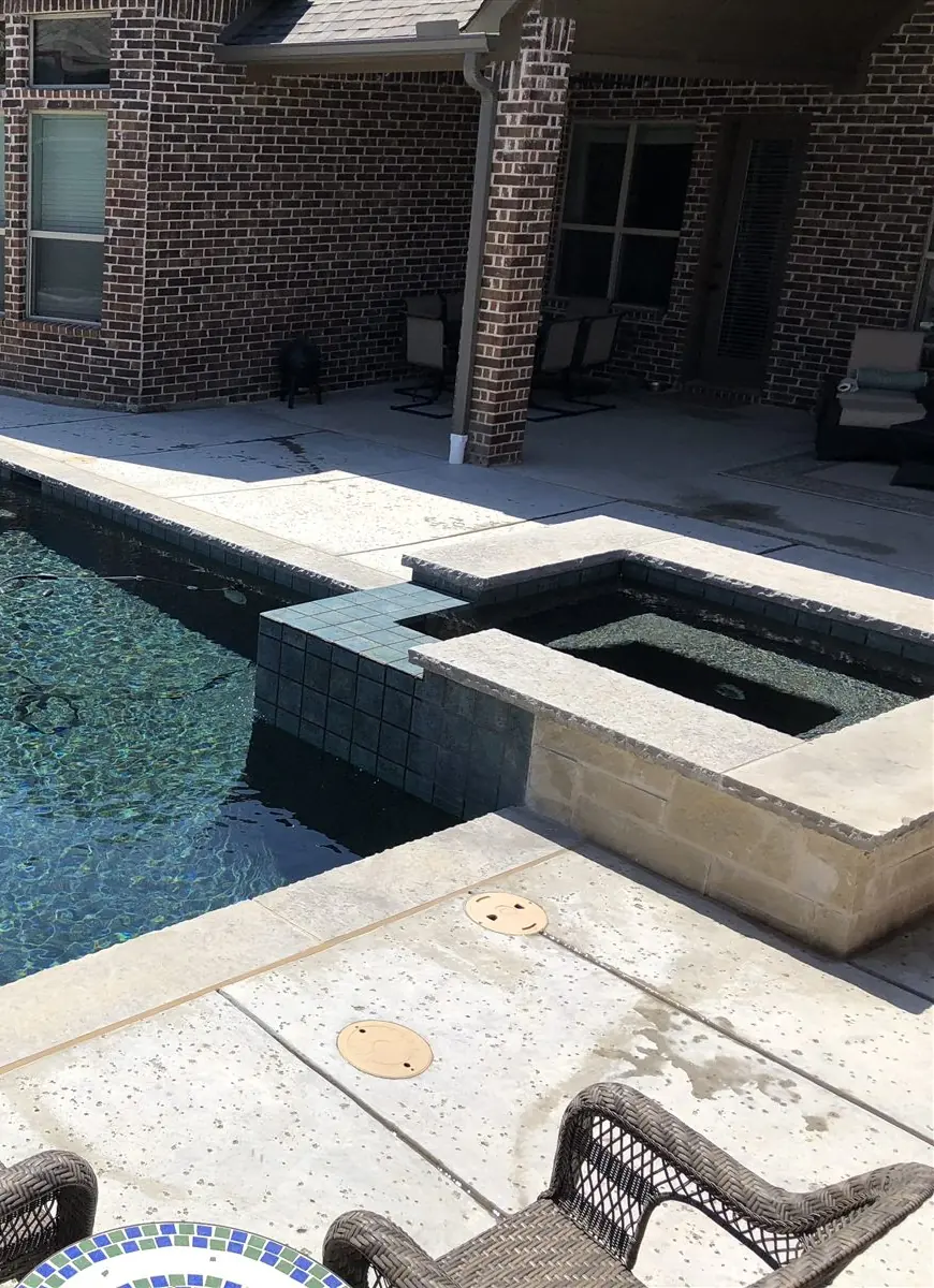 Dark rectangle pool and spa beside a brick house