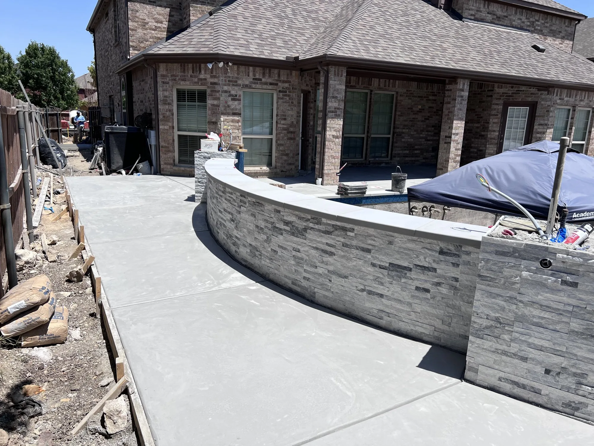 Concrete deck and a stacked-stone wall during a Lucent pool build