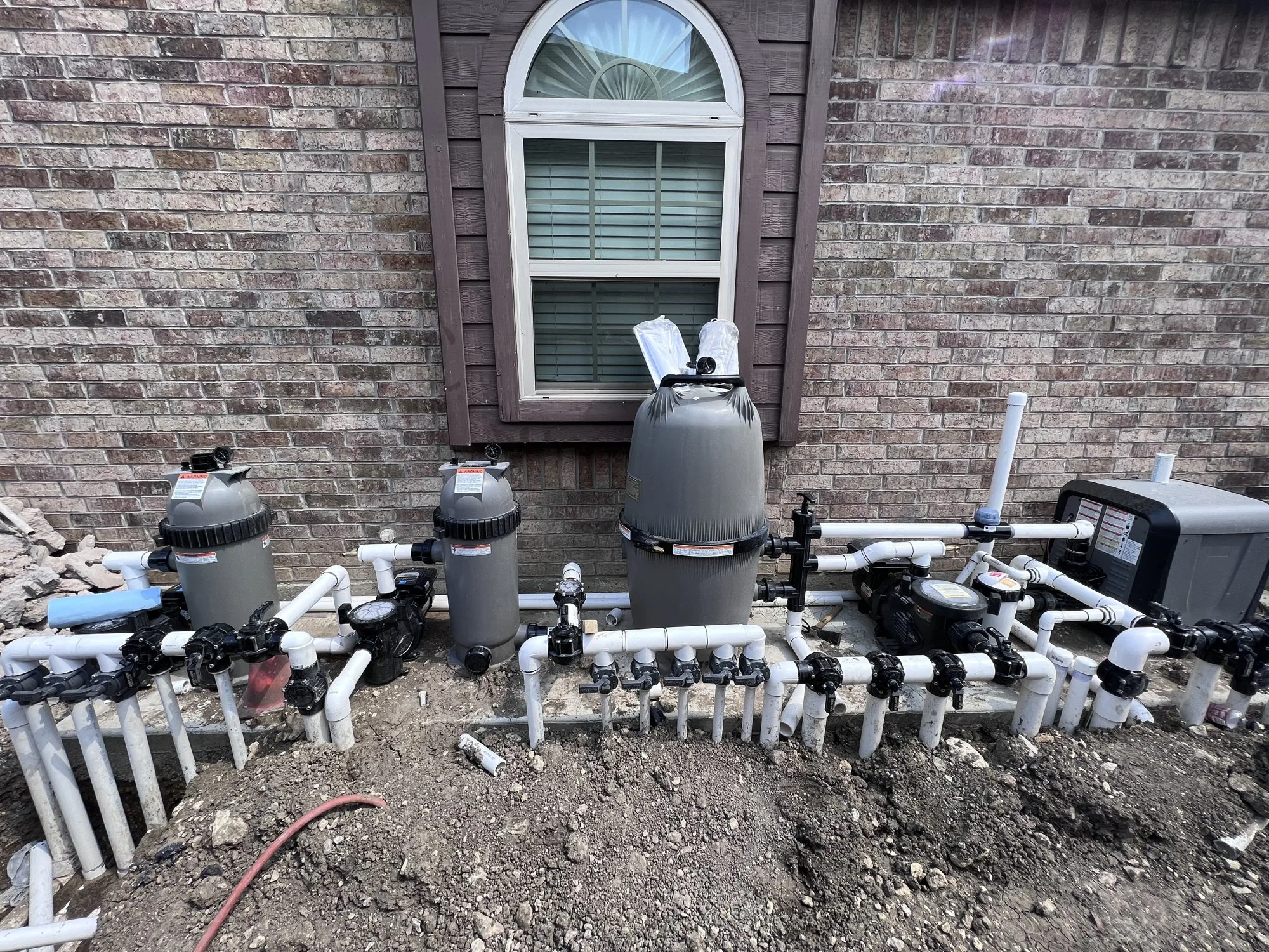 Pool filters, pumps, and a heater on the equipment pad of a Lucent pool build