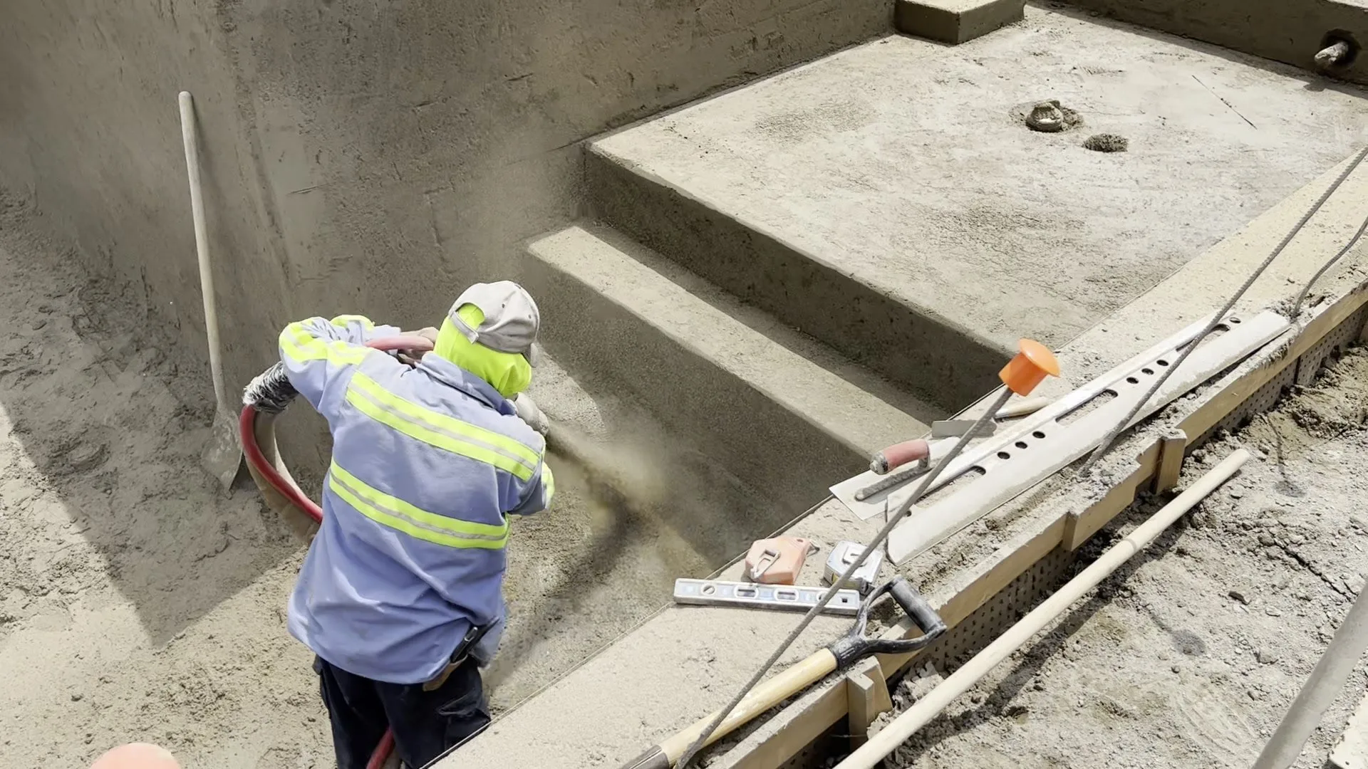 Worker spraying gunite on pool steps during a Lucent pool build
