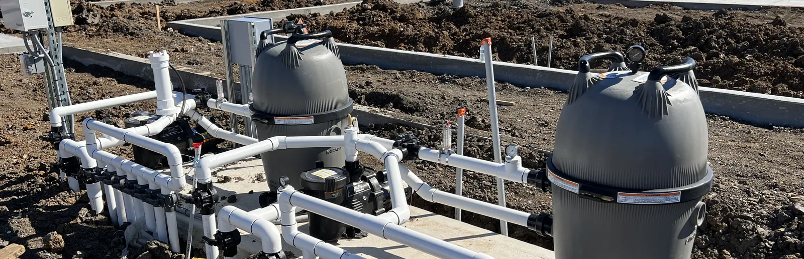 Equipment pad for the Hollyhock center fountain in Frisco, TX, during install, with two large cartridge filters, pumps, and a valve manifold