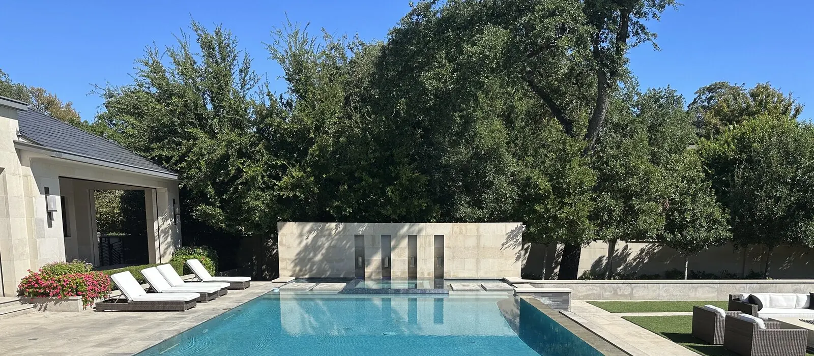 Rectangle pool with a stone feature wall and lounge chairs