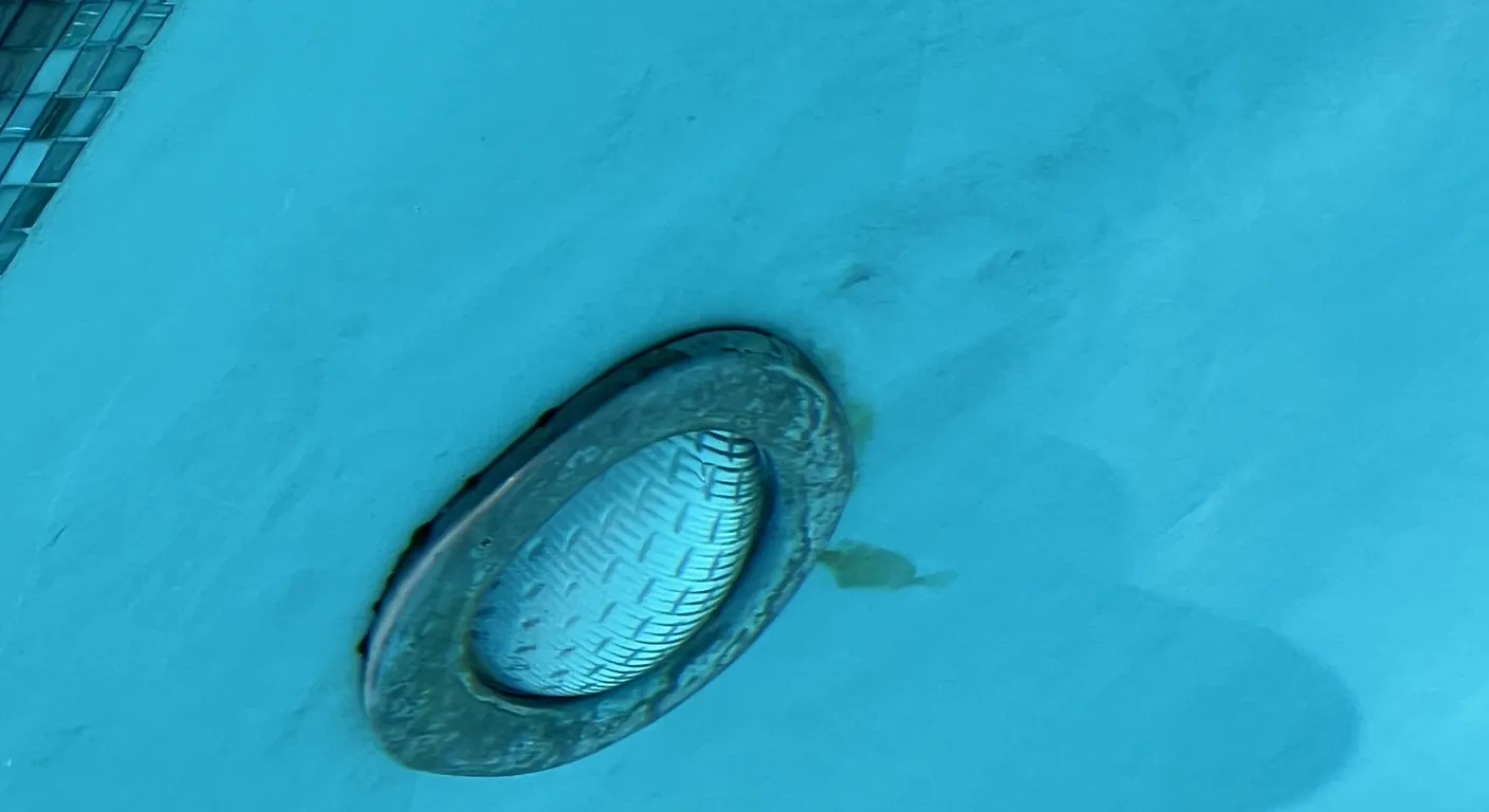 Pool light with a stained metal ring in a blue pool wall