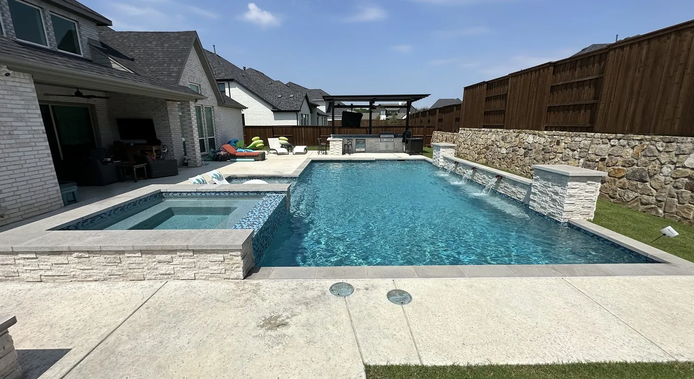 Clean rectangle pool with raised spa and stone water features in DFW.