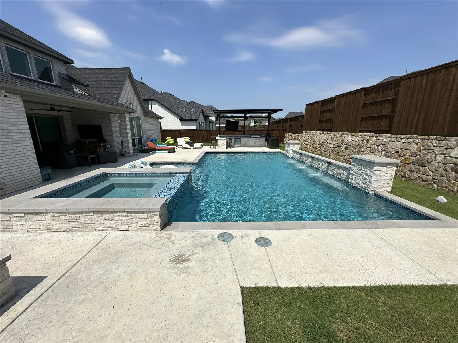 Rectangle pool with a raised stone spa and sheer descent water features