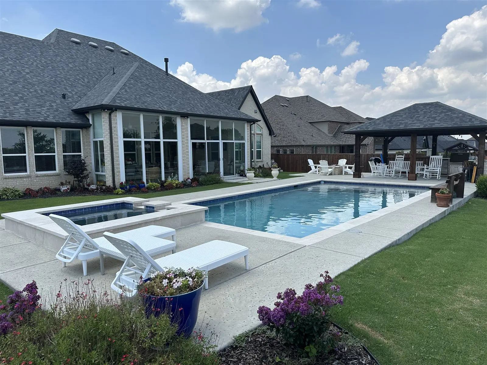 Rectangle pool with a raised spa, lounge chairs, and a gazebo