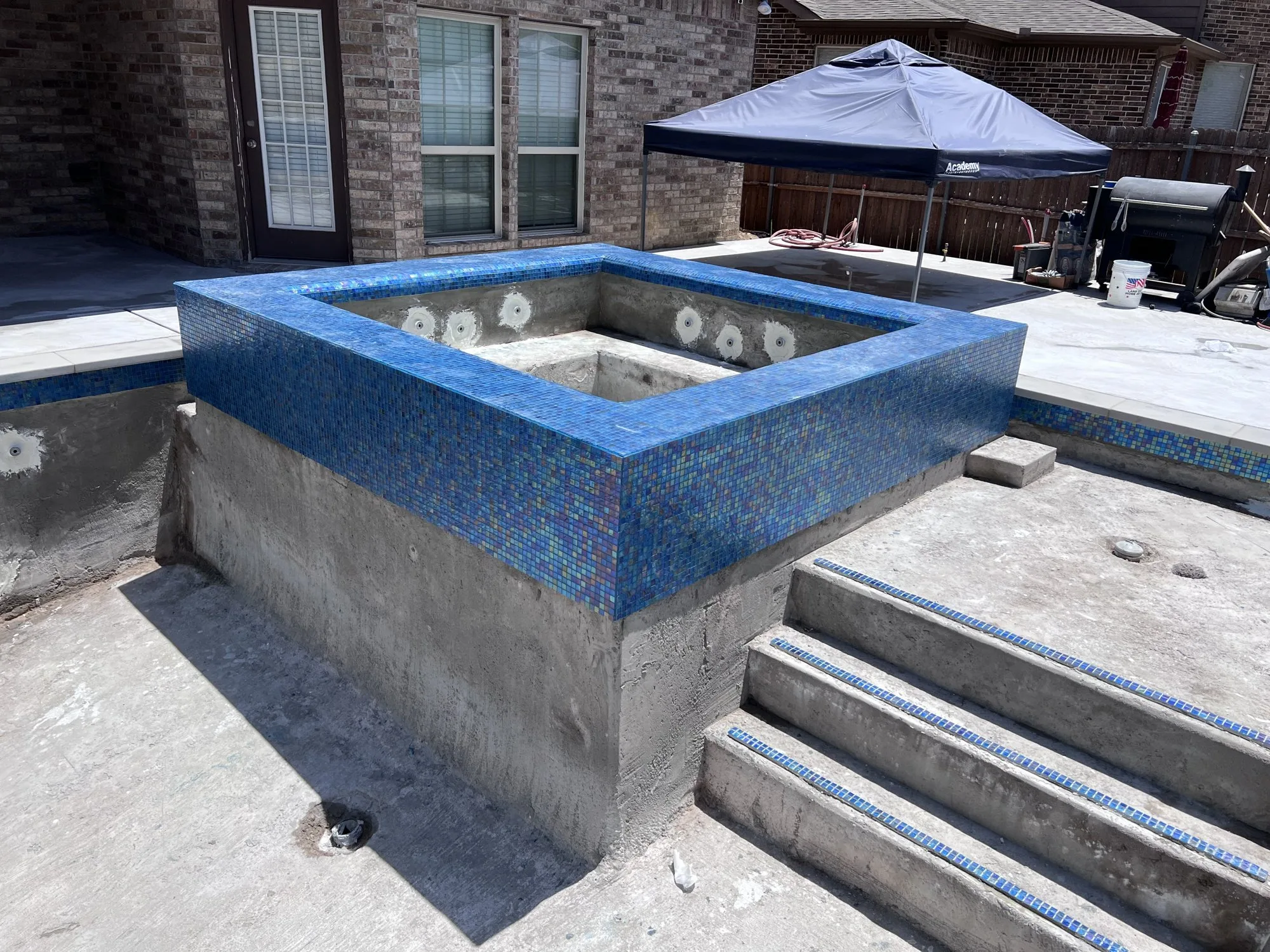 Raised spa with blue glass tile during a Lucent pool build