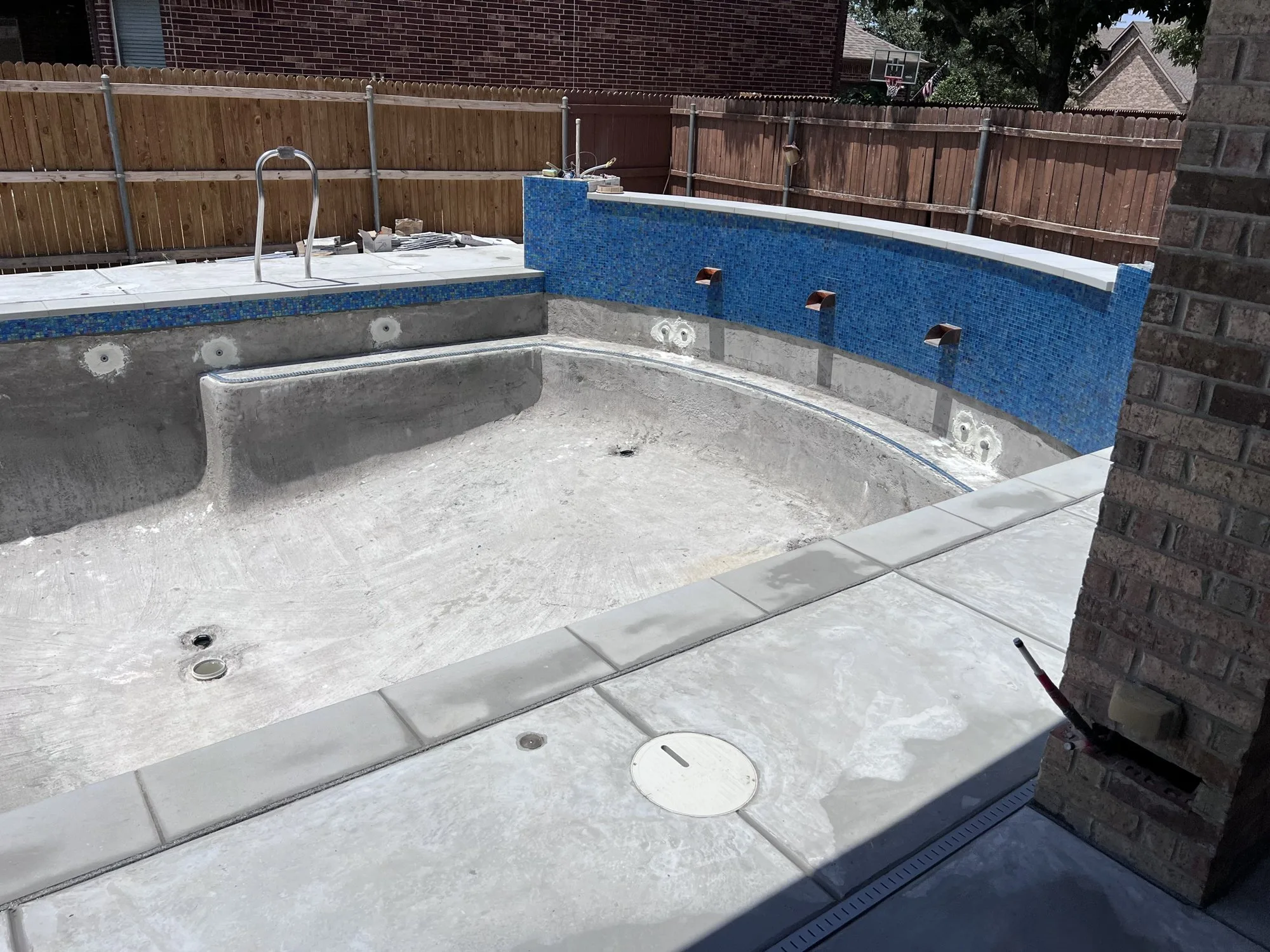 Blue waterline tile and light coping on a Lucent pool build